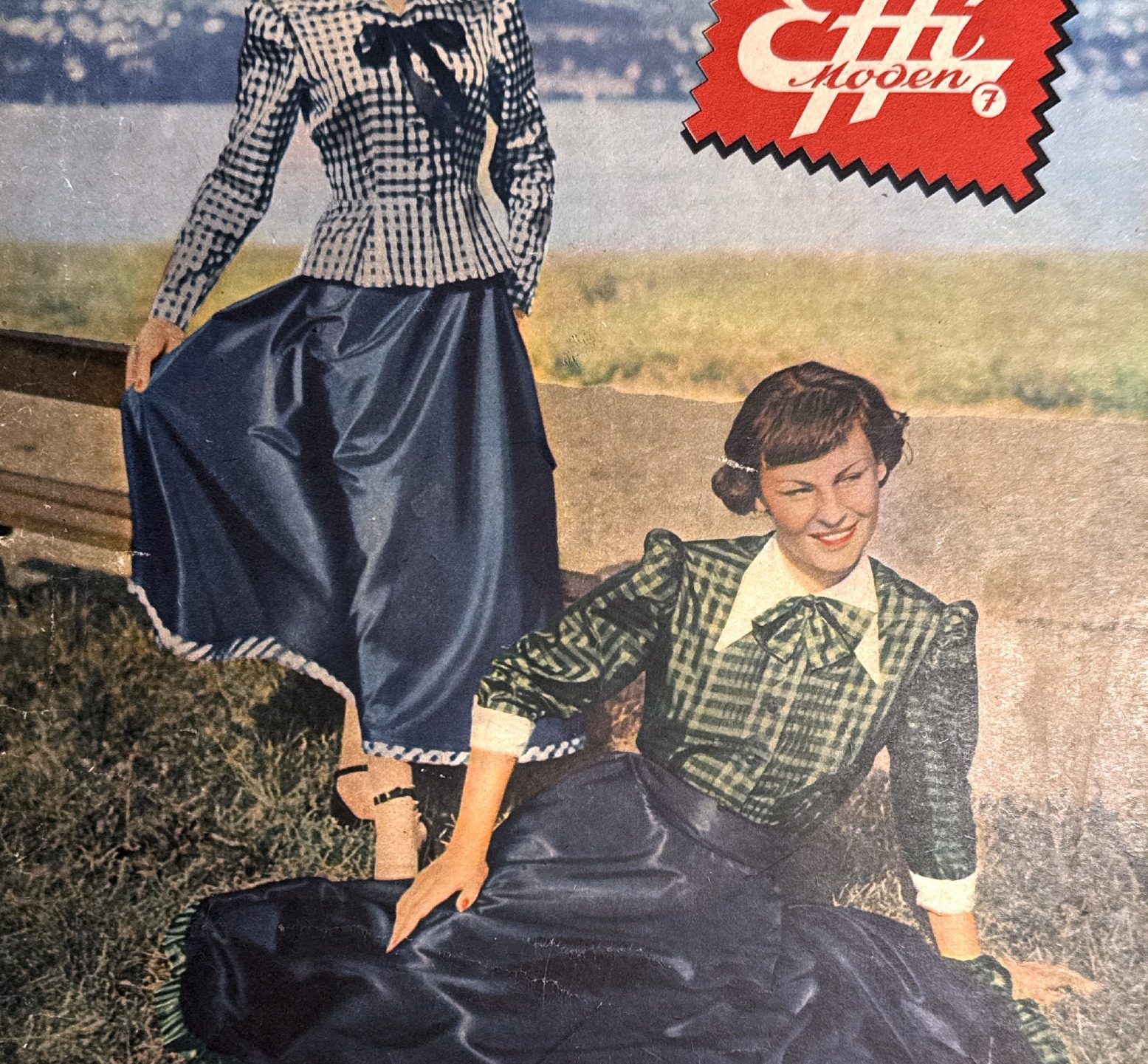 Detail of two women in gingham and plaid blouses with full skirts by a lake
